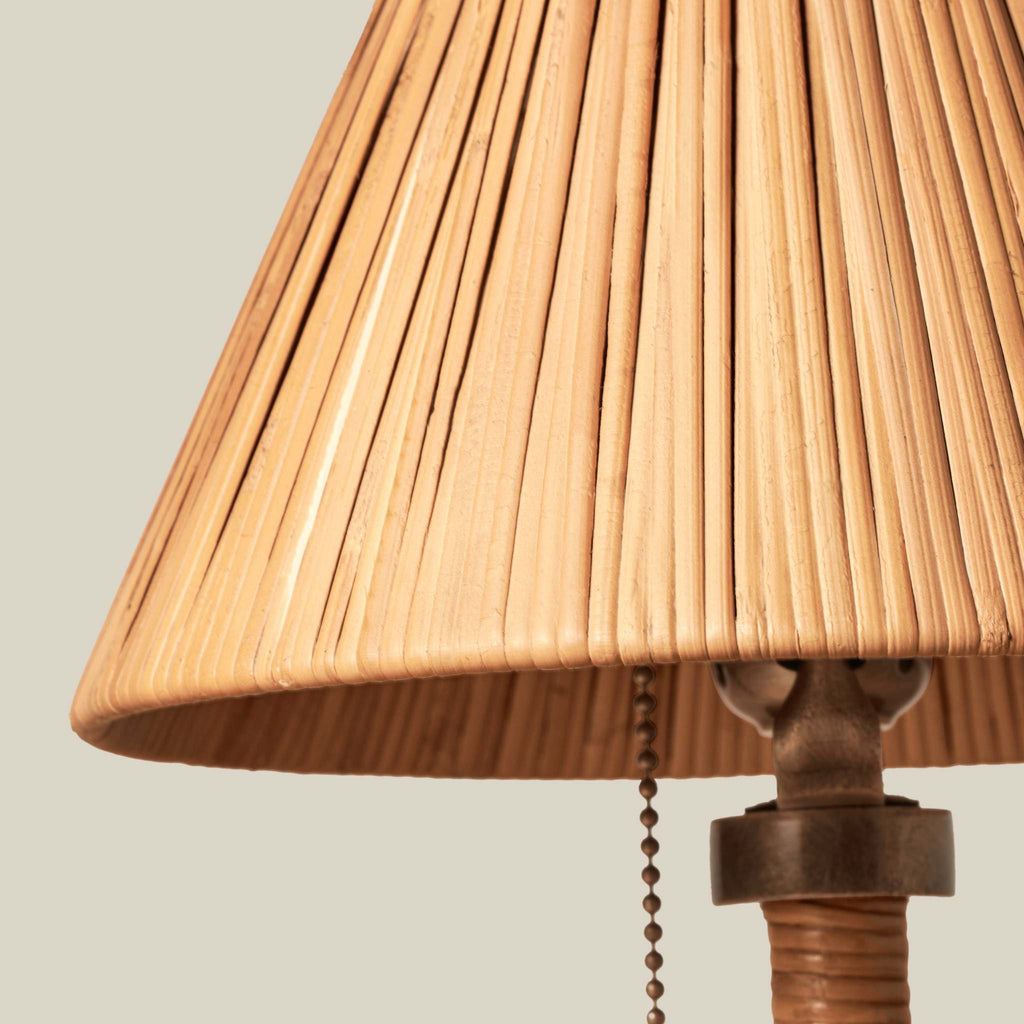 Close-up of a mini Delphine table lamp lampshade with a dark metal pull chain and a textured brown base against a solid light beige background.