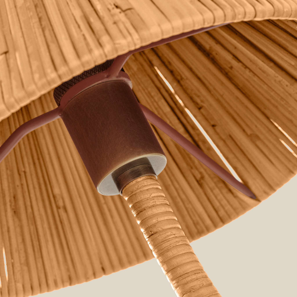 Close-up detail of a Delphine Sconce lampshade and stem, showing a woven natural fiber shade in warm tan tones, a dark brown central collar, and a ribbed brown stem against a light neutral background.