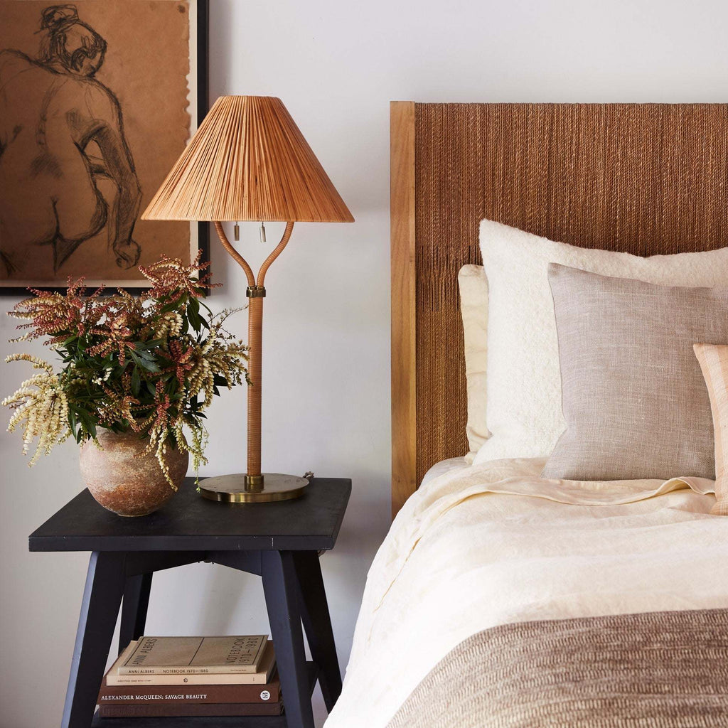 Bedroom with a bed, Delphine table lamp, and decorative items on a nightstand.