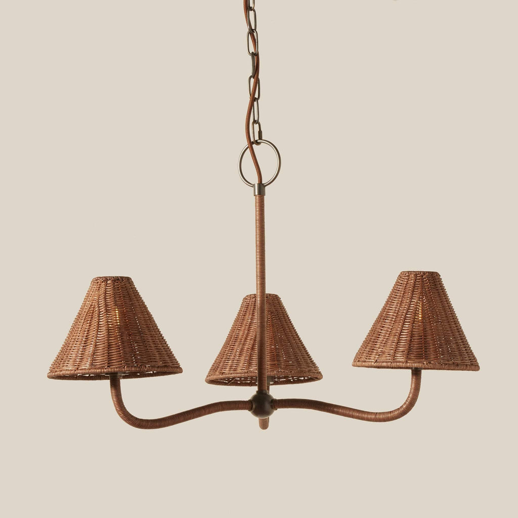 Delphine three-light wicker chandelier with pewter metal frame and matching wicker shades, suspended from a chain against a solid beige background.