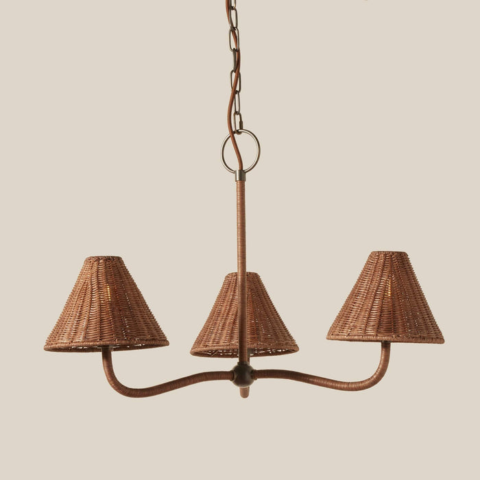 Delphine three-light wicker chandelier with pewter metal frame and matching wicker shades, suspended from a chain against a solid beige background.