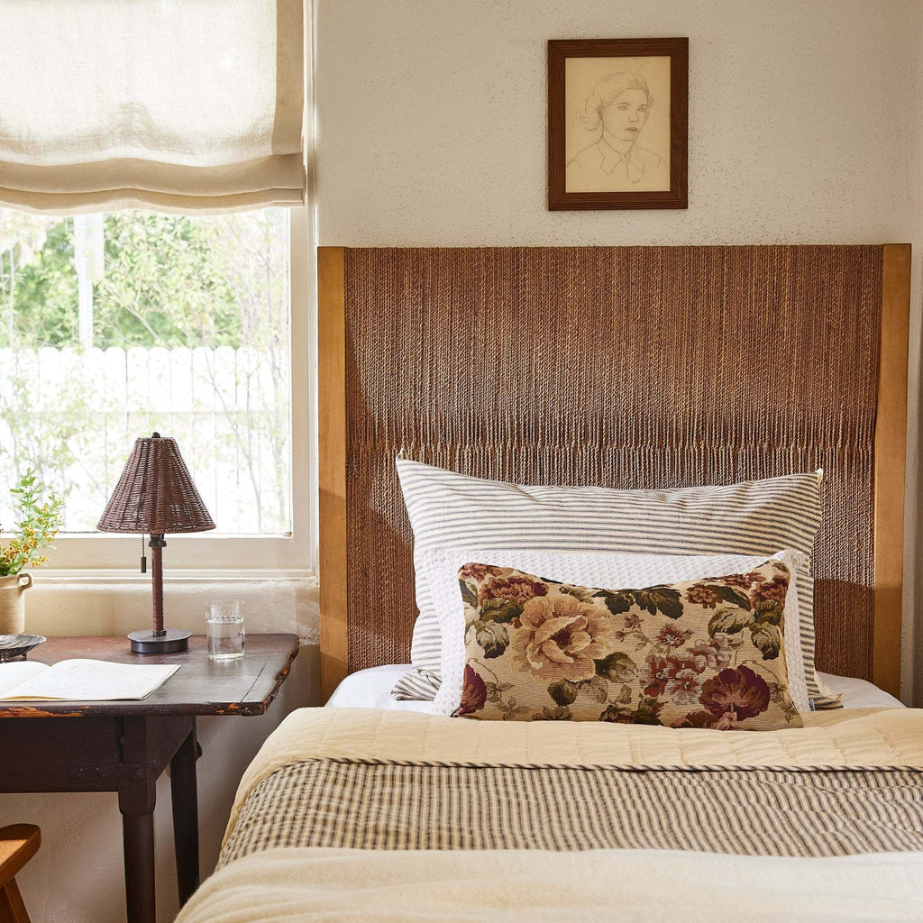 Bedroom with wooden headboard, floral pillow, and Delphine table lamp on a nightstand.