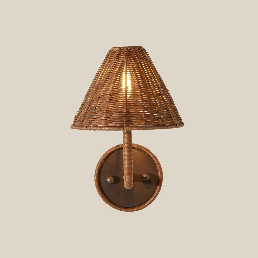 Delphine wicker wall sconce with a conical woven shade and a round backplate, shown against a solid light beige background.