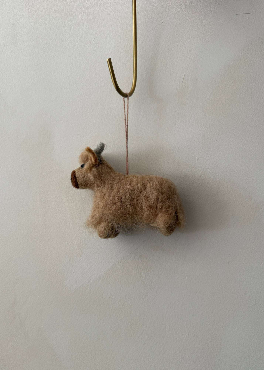 Handcrafted felt Highland cow ornament made from natural wool with a shaggy design for rustic home decor or holiday decoration