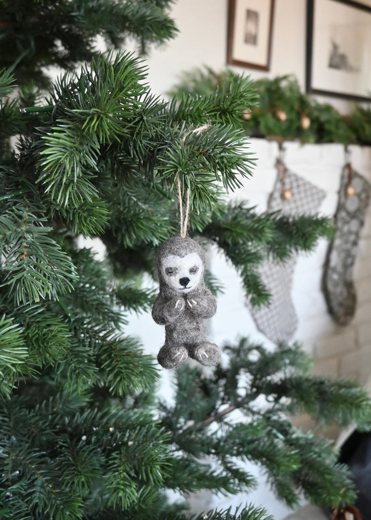 Felted yoga sloth ornament hanging on a Christmas tree. Saffron + Poe