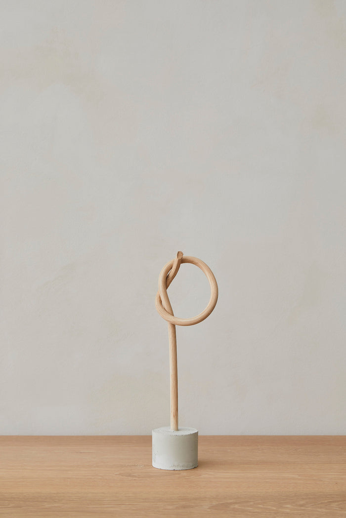 Front view of Katie Kong Small Wood Knot Sculpture on an Oak Dining Table against a white wall. - Saffron and Poe