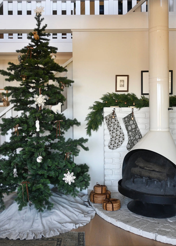 Decorated Christmas tree next to a fireplace with stockings hanging.