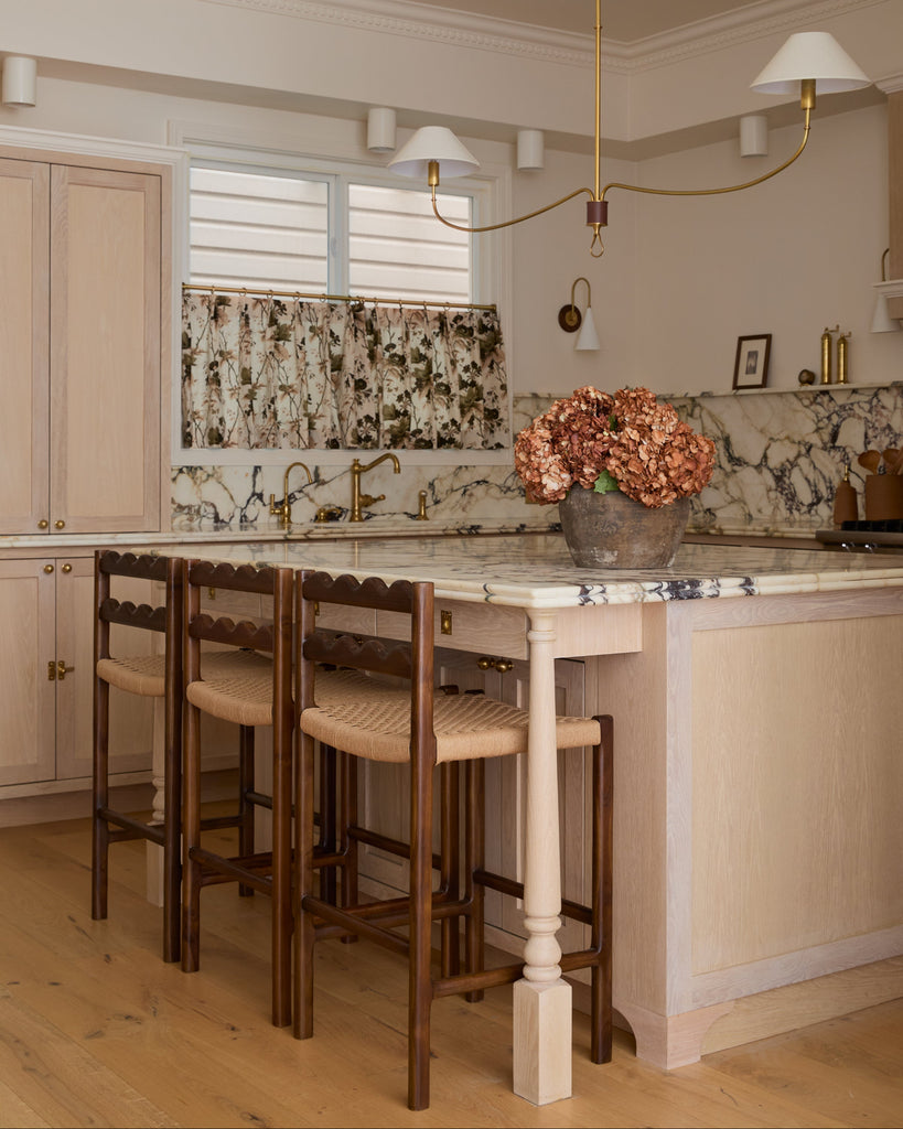Ionian scalloped counter stool with woven seat in white oak kitchen with marble counters. Saffron and Poe