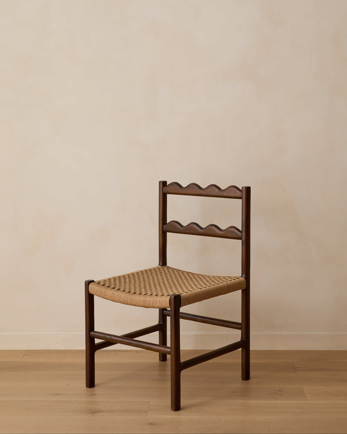 Ionian scalloped dining chair with woven seat on white oak flooring against a beige wall. Saffron and Poe