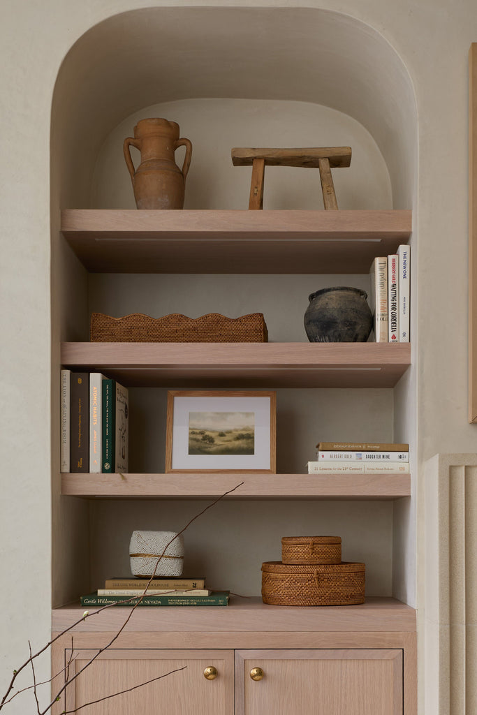 Built-in shelving niche with white oak shelves and styled with tenganan basket accessories and books. 