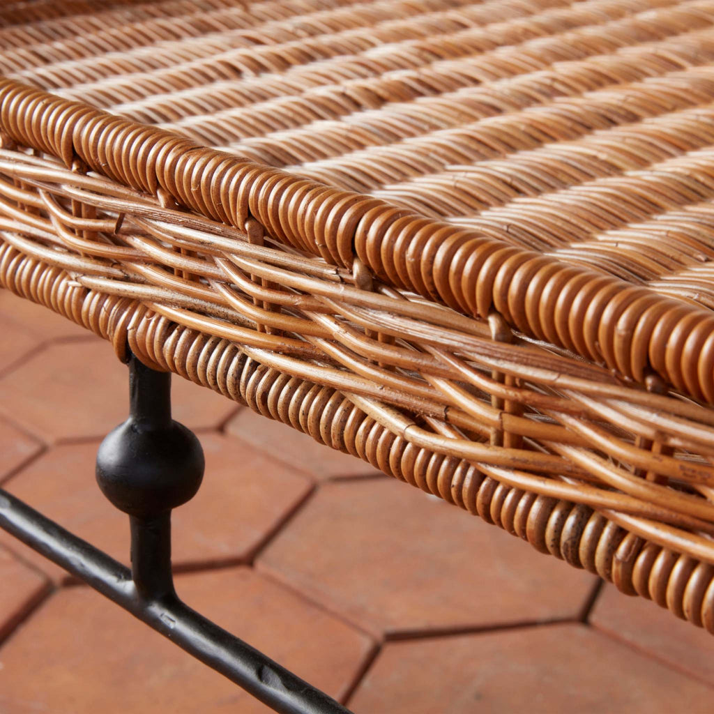 Close-up of rattan indoor-outdoor coffee table with metal iron base on a terracotta floor.