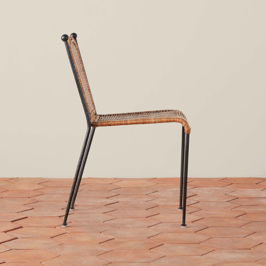 Rattan Lacoste Indoor-Outdoor Dining chair with metal legs on a terracotta tile floor.