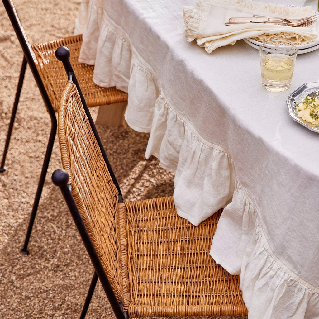 Lacoste Indoor-Outdoor Dining Chairs at an outdoor table setting with a white linen tablecloth. 