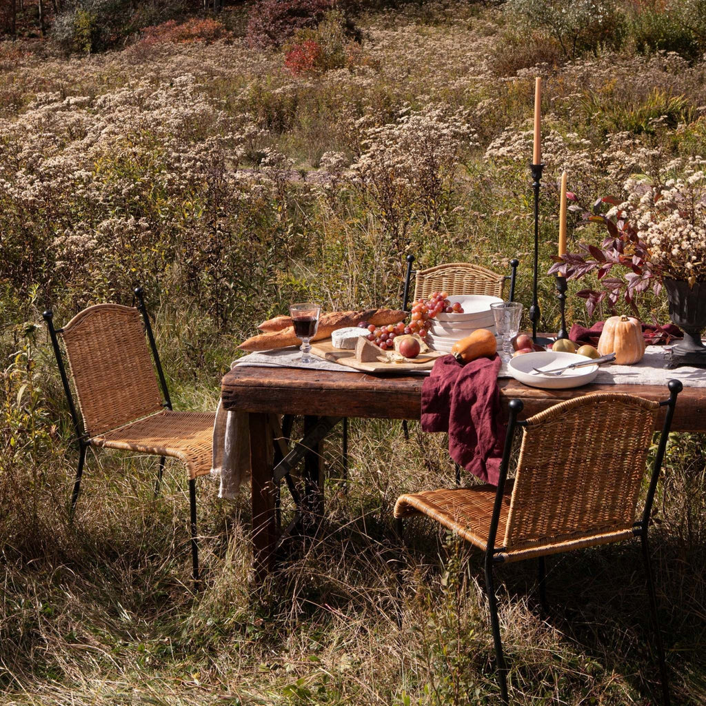 Outdoor dining setup with Lacoste Indoor-Outdoor Dining Chairs paired with a rustic wooden table in an outdoor meadow setting.