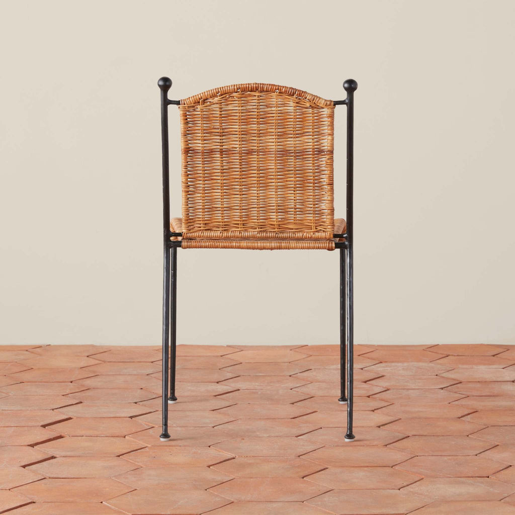 Rattan Lacoste Dining Chair with black metal frame on a hexagon-shaped tile floor.