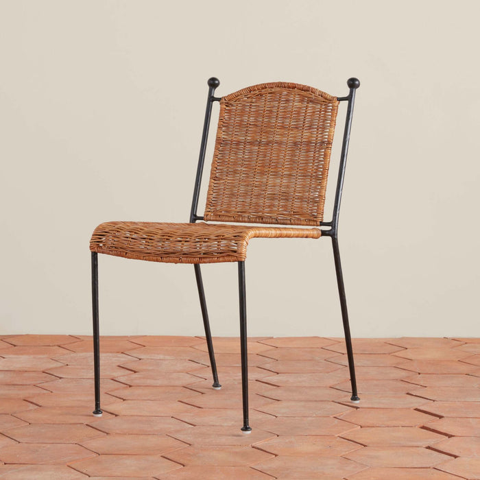 Lacoste rattan indoor-outdoor dining chair with metal frame on a tile floor and beige background. 