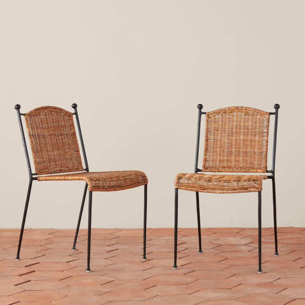 Two Lacoste Indoor-Outdoor Dining chairs with black metal frames on a tile floor against a beige wall.