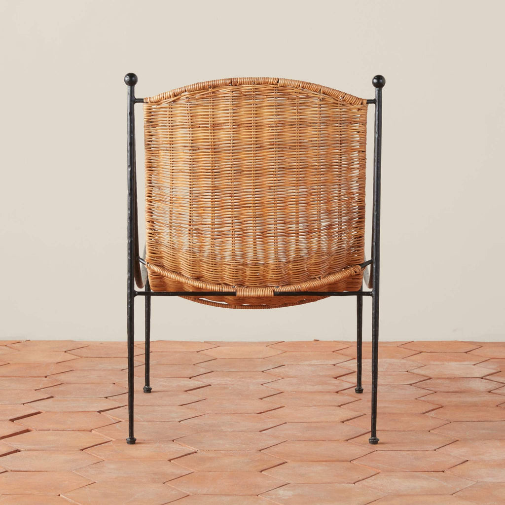 Back view of Lacoste wicker chair with metal frame on a terracotta tile floor.
