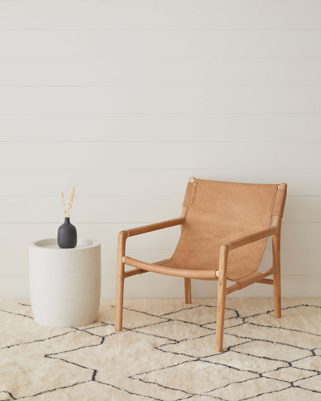 Leather sling lounge chair with carved teak frame and beige leather upholstery
