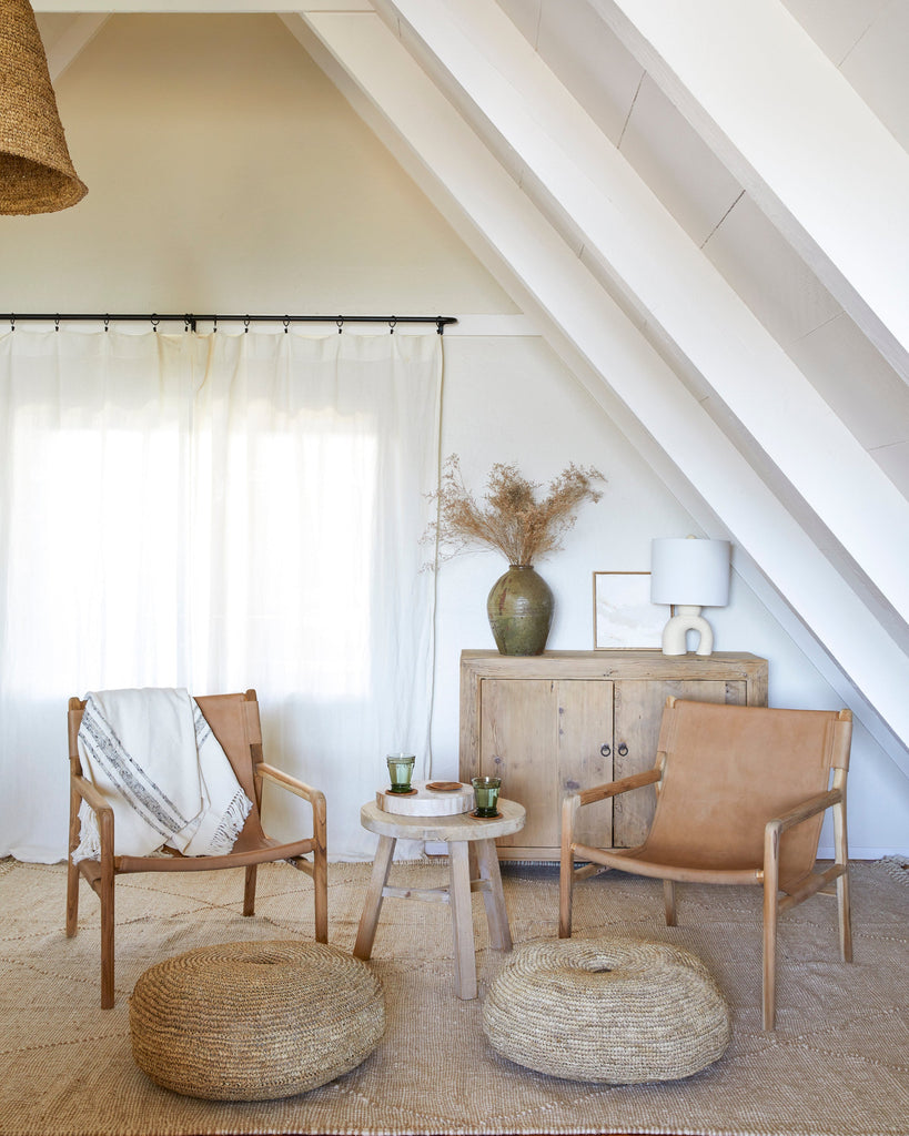 Beige leather sling lounge chairs in a living room with wooden furniture and decorative items.