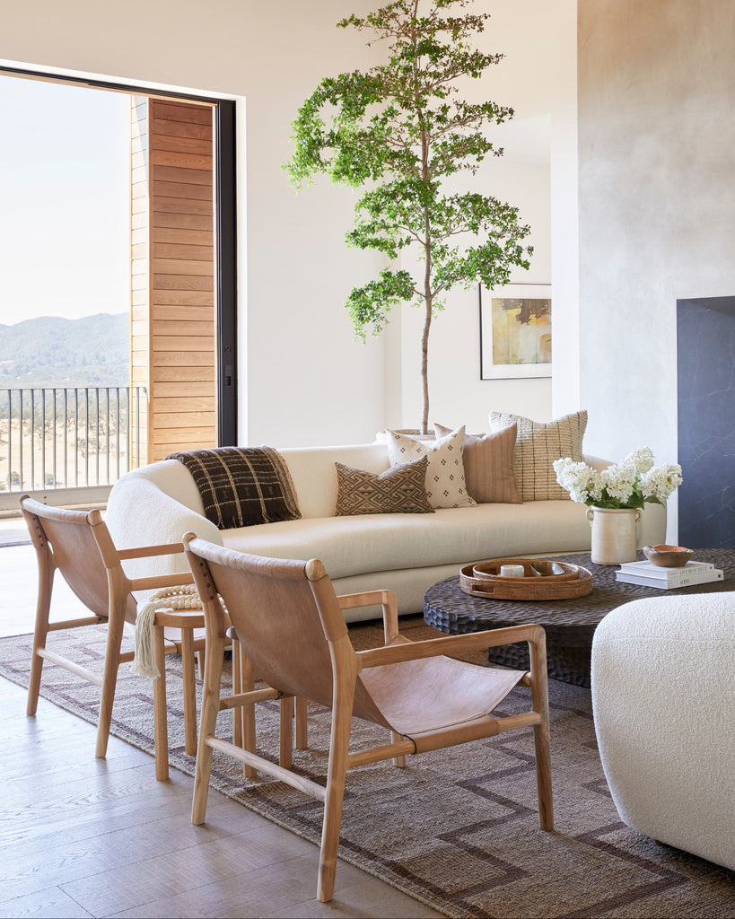 Modern living room with a white sofa, sling lounge leather chairs, and decorative elements.
