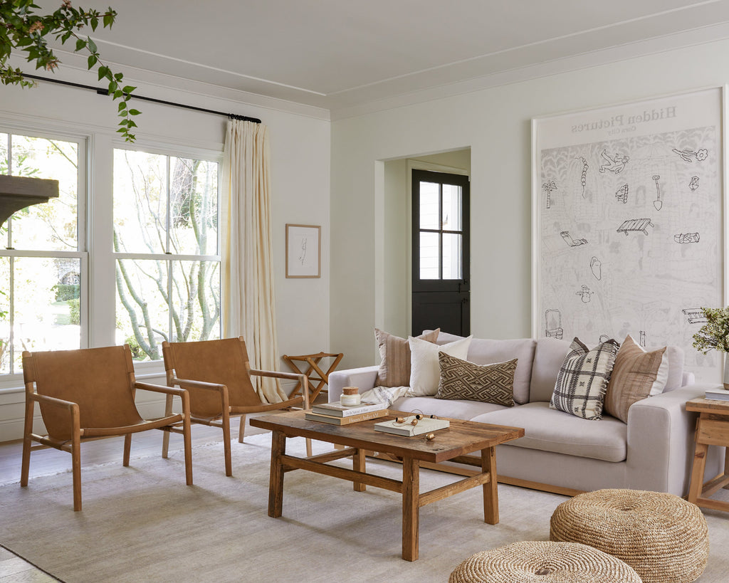 Living room with beige sofa, wooden coffee table, and leather sling lounge chairs.