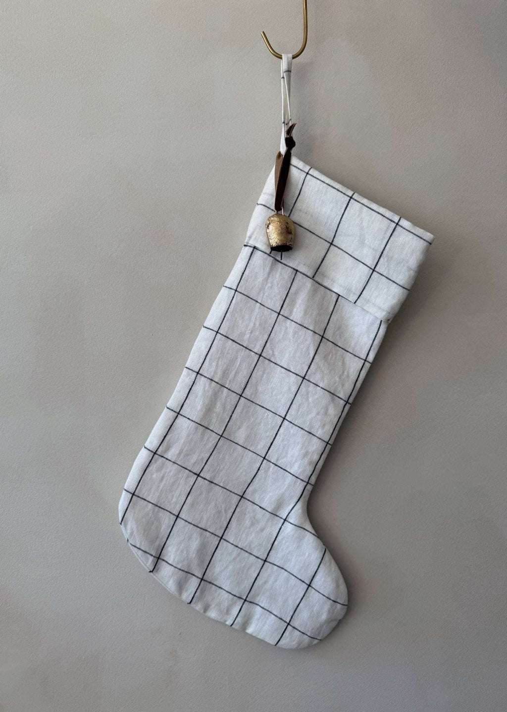 Natural linen stocking with checkered pattern and antique bell accent tied with cinnamon ribbon