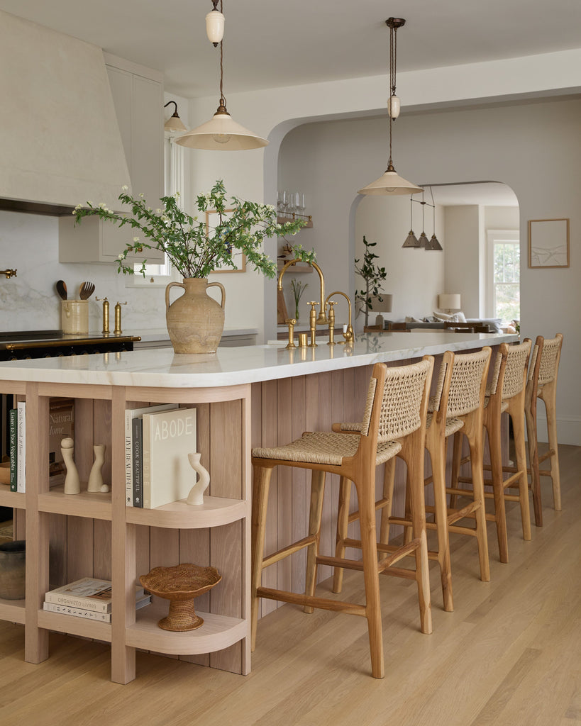 Marin Faux Rattan Counter Stool in modern timeless kitchen with white oak and cream cabinets, angle view.