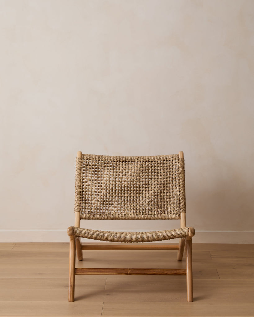 Marin faux rattan Lounge Chair on a white oak floor with a beige wall background