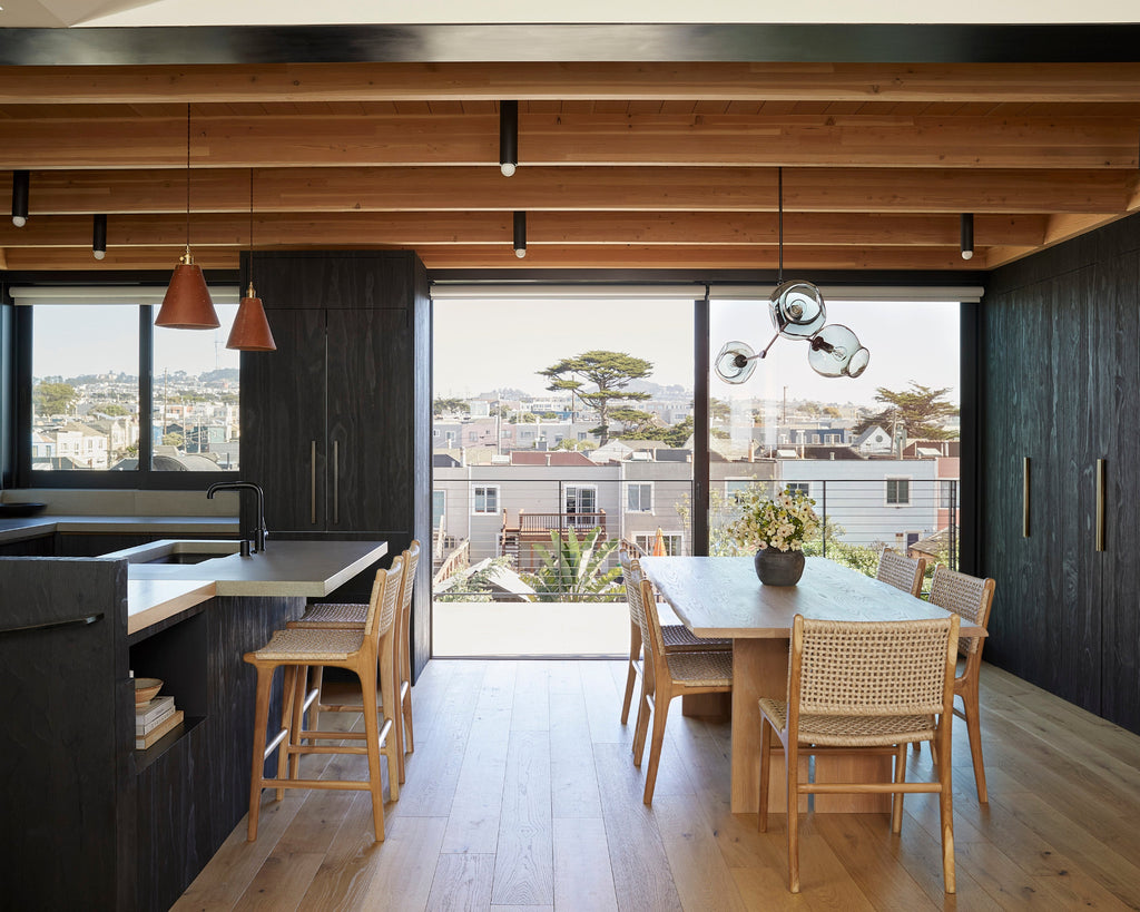 Dining room with wooden table and faux-rattan Marin dining chairs, vase with flowers on the table.