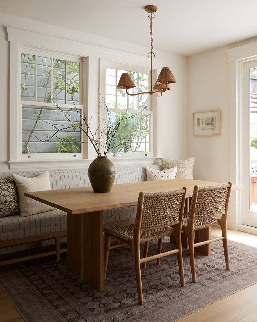 Dining room with wooden table and faux-rattan Marin dining chairs, vase with branches on the table.