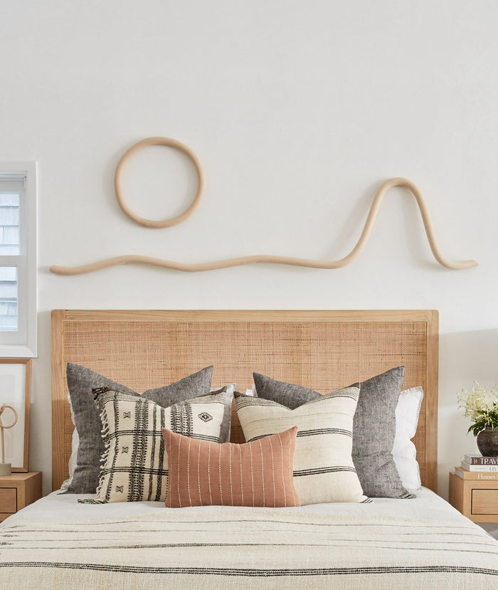 Katie Gong Wood Sculpture Art shot in bedroom above rattan headboard  and woven leather bench. Saffron + Poe, Katie Gong