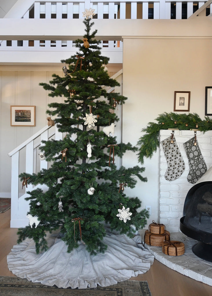 Decorated Christmas tree in a living room with stockings and a fireplace.