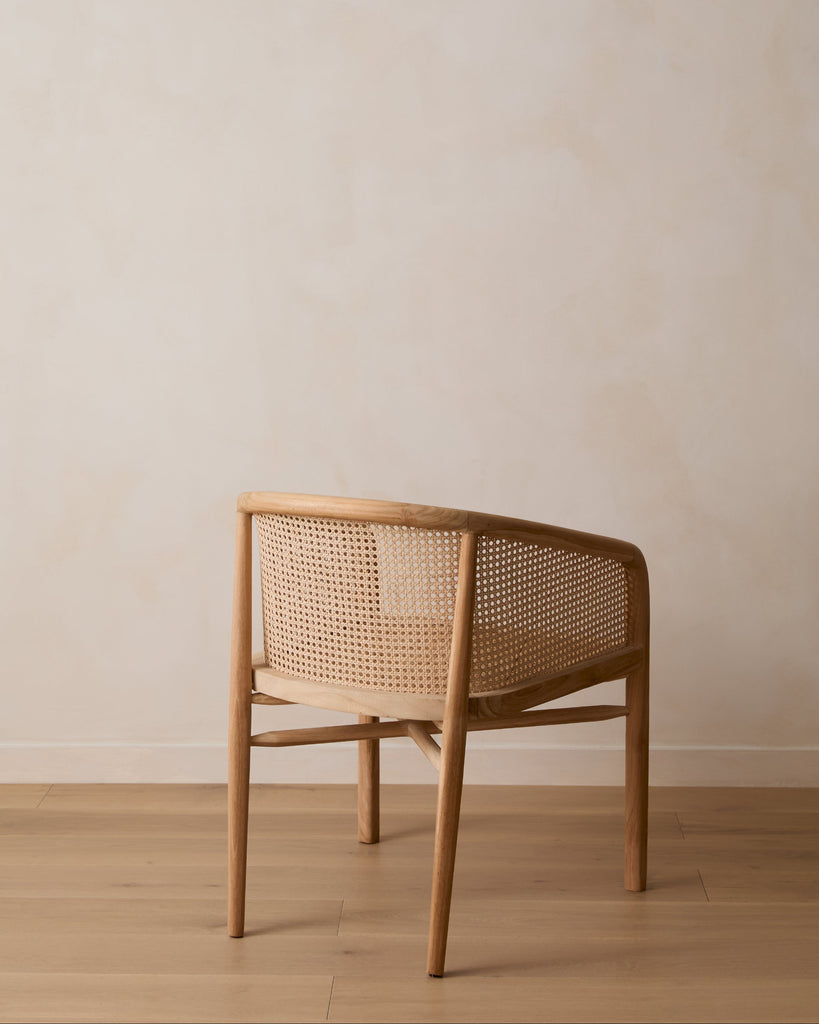 Olivia Rattan Accent Chair on white oak floor against limewashed wall. Saffron + Poe
