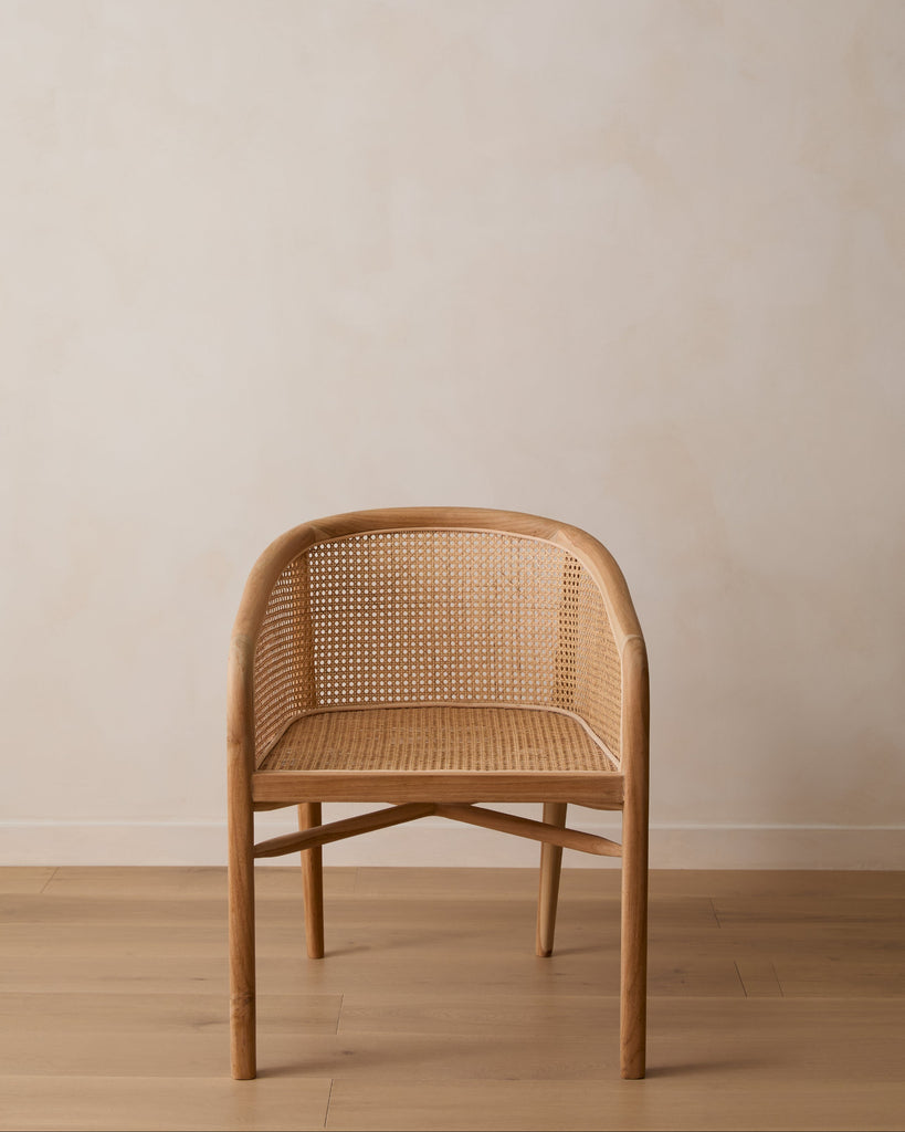 Olivia Rattan Accent Chair on white oak floor against lime washed wall. Saffron + Poe