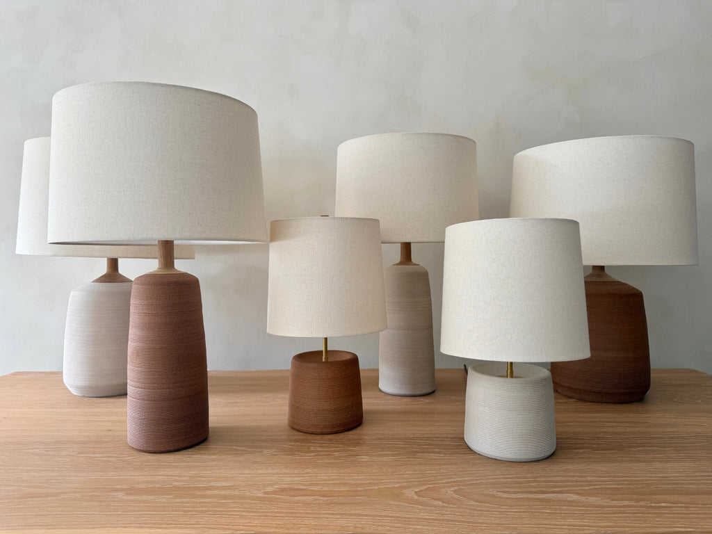 Ostuni, Ravello and Pienza Ceramic Table Lamps with oatmeal linen shades grouped on a white oak table. - Saffron + Poe