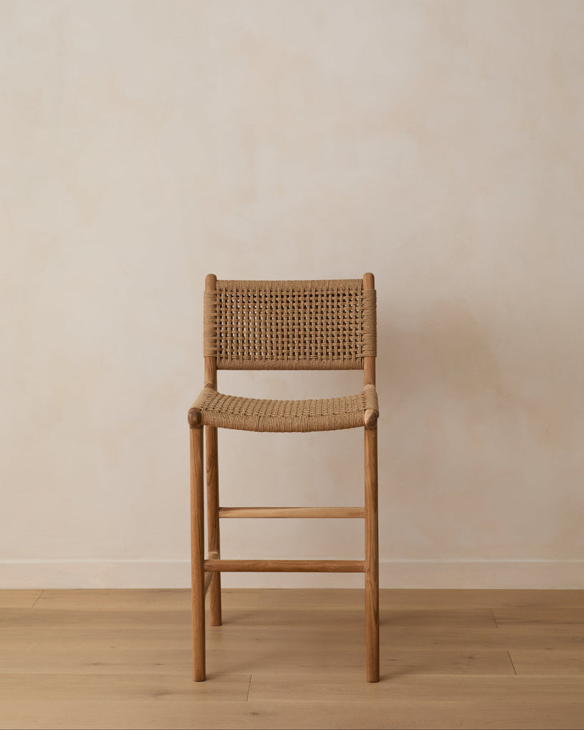Paper cord counter stool with woven seat against a limewash wall.