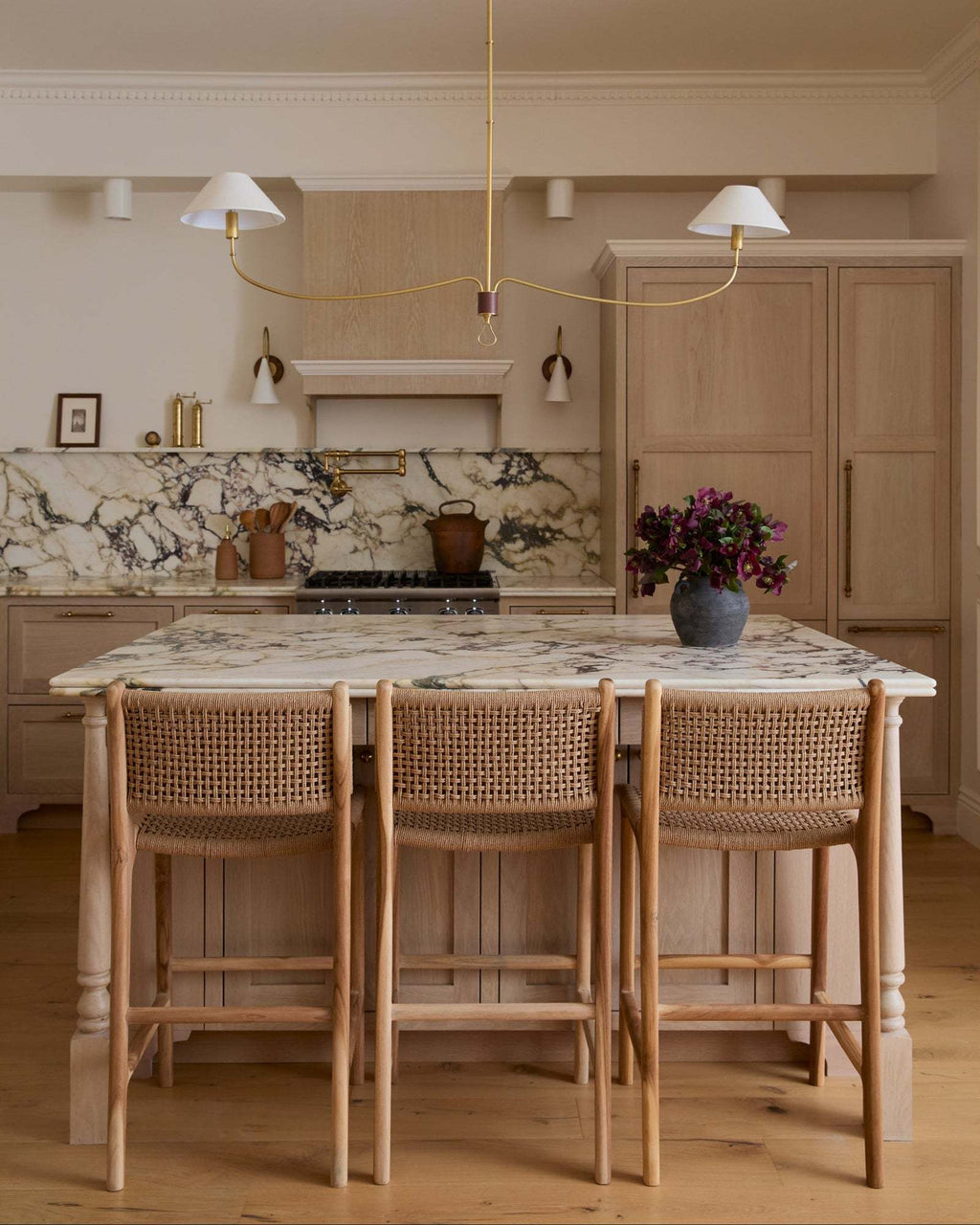 Modern kitchen with marble island, paper cord counter stools, and pendant lights.