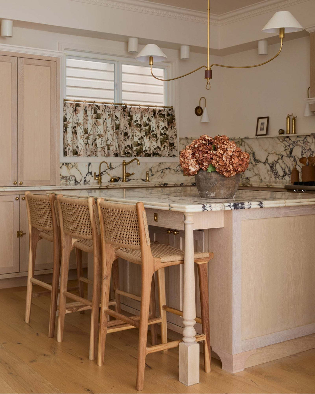 Modern kitchen with marble island, paper cord counter stools, and decorative elements.