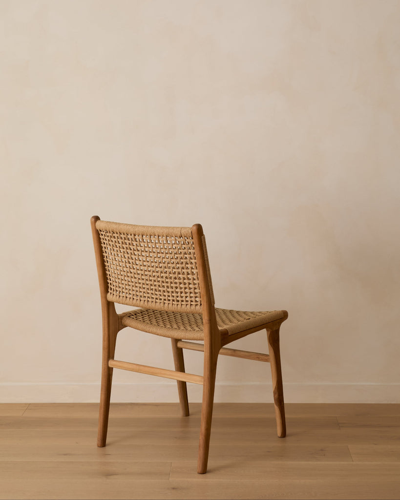 Teak chair with paper cord backrest against a beige limewash wall