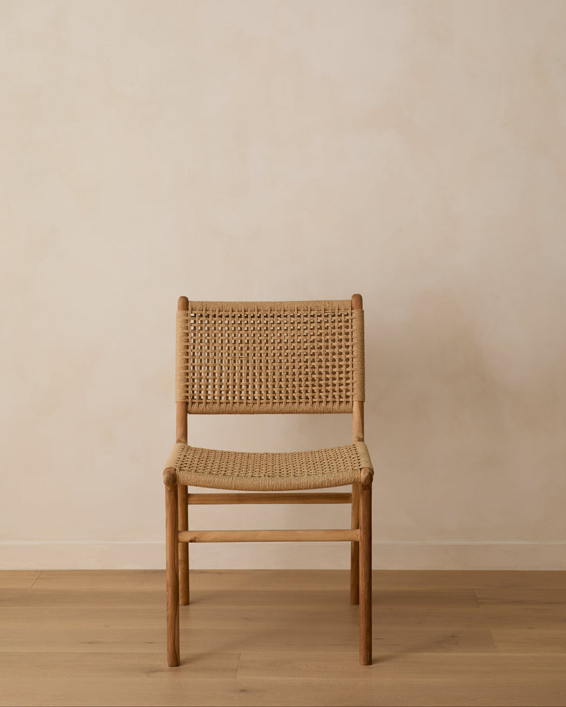 Teak chair with paper cord backrest and seat against a plain wall.
