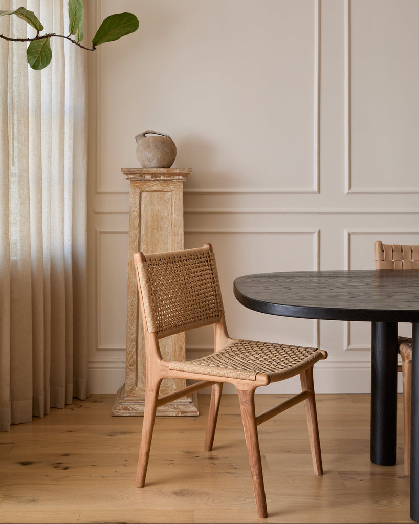 Teak dining chair and table in a room with neutral walls and decor.