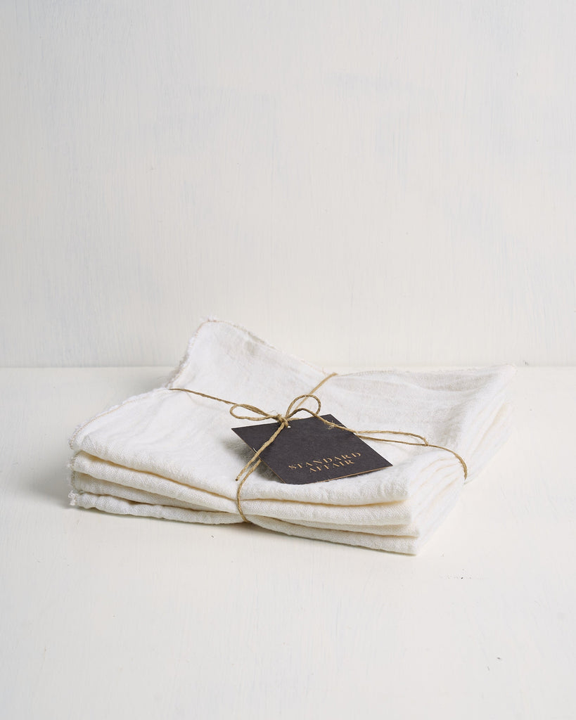 Folded white Philo Linen Napkins with a black tag on a light gray background