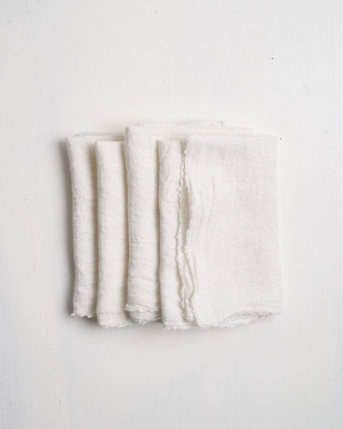 Folded white Philo Linen Napkins on a light gray background