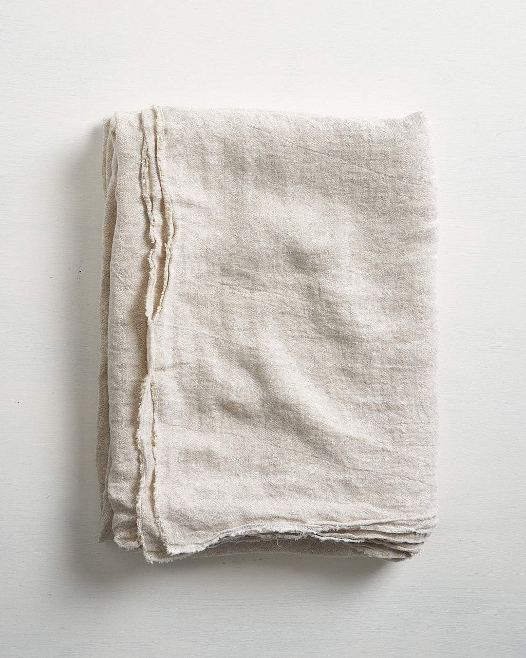 Folded beige tablecloth on a light gray background