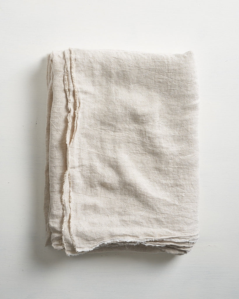 Folded beige tablecloth on a light gray background