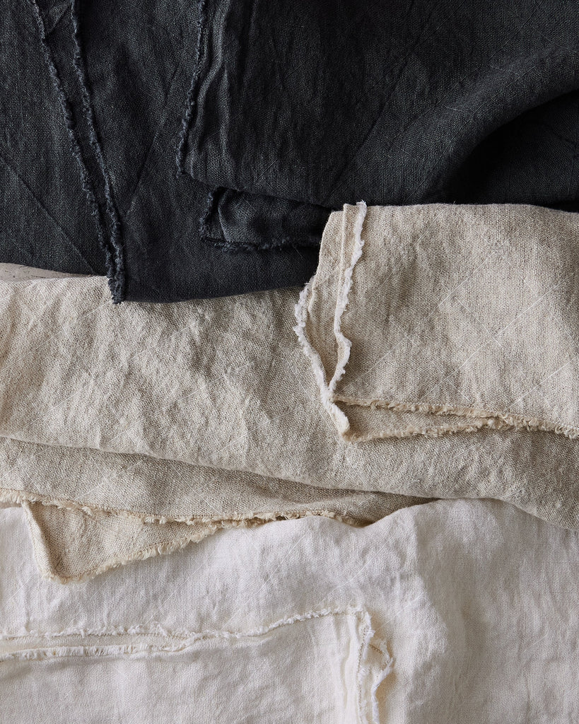 Stack of black and white philo tablecloths with frayed edges