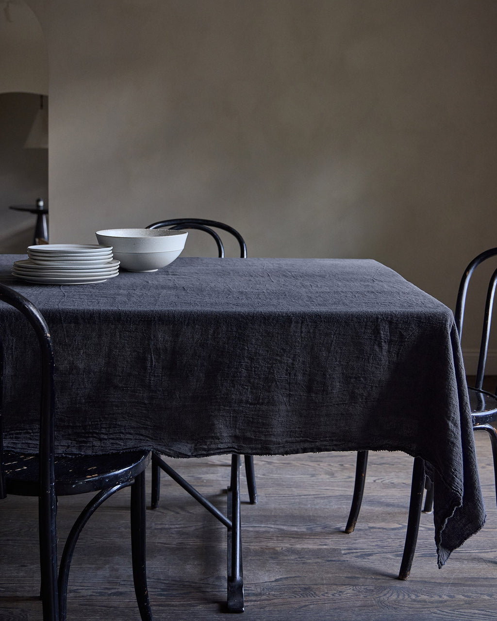 Dining table with a slate Philo linen tablecloth and white bowls in a minimalistic setting.