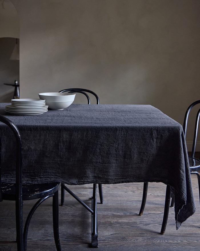 Dining table with a slate Philo linen tablecloth and white bowls in a minimalistic setting.