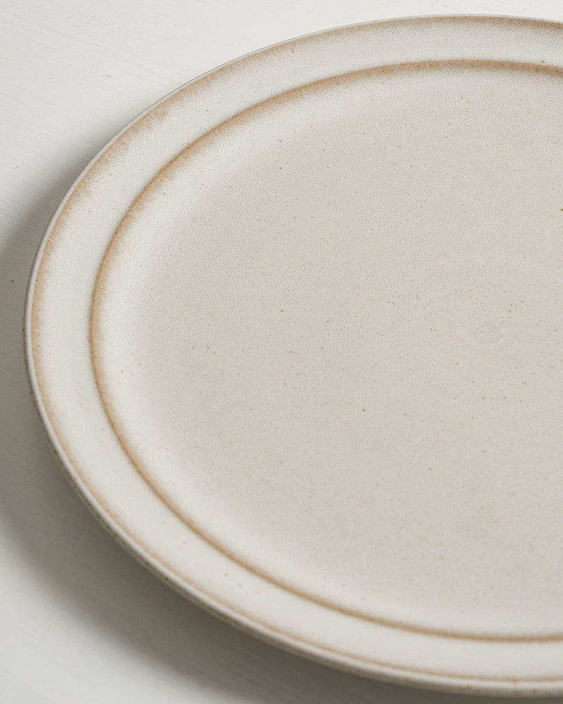 Close-up of a ceramic Pillar Dinner plate with a beige rim on a light background